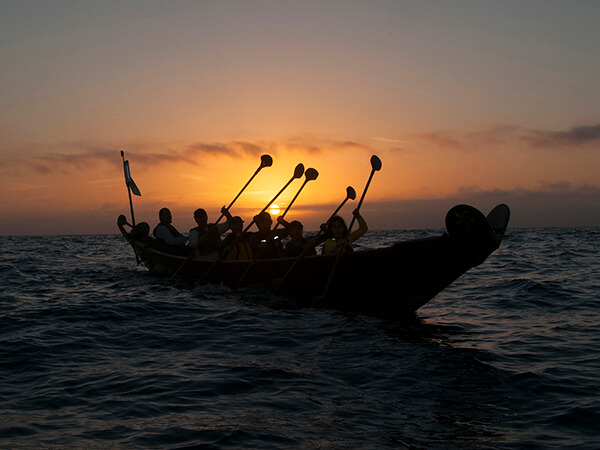 A tomol being rowed at sunrise